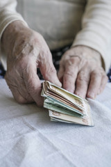 Closeup of wrinkled hands counting turkish lira banknotes