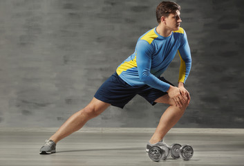 Young handsome sportsman doing exercises on color background