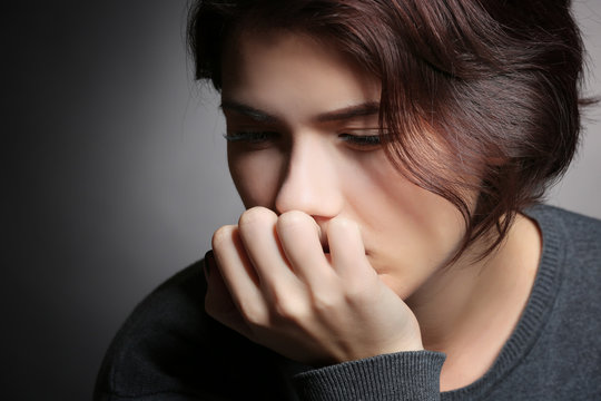 Depressed young woman on grey background, closeup