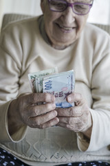 Closeup of a happy senior woman counting turkish lira banknotes