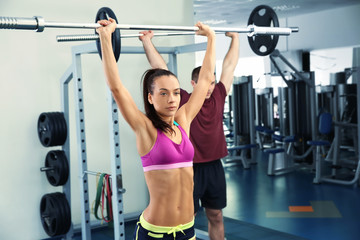 Fototapeta premium Young beautiful woman with barbell training in gym