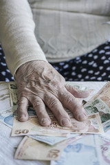 Closeup of wrinkled hand counting turkish lira banknotes