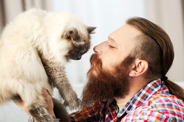 Young bearded man with fluffy cat at home