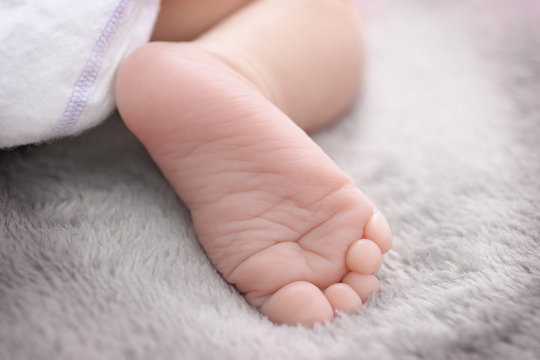 Foot of cute baby lying on bed, closeup