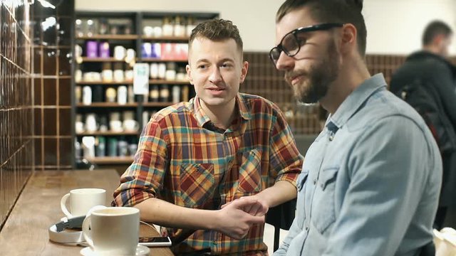 Man pointing on something in the cafe and talking with his friend, steadycam shot
