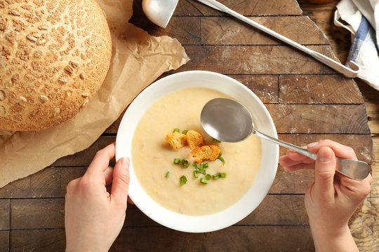 Female hands and delicious cream soup on table