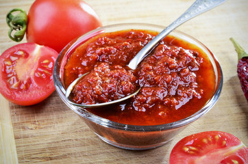 Tomato chutney in a glass bowl on a wooden background