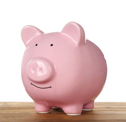 Pink piggy bank on wooden table against white background