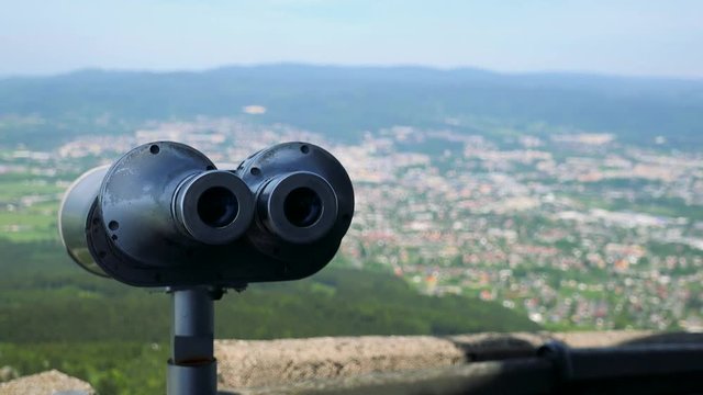 Sightseeing binoculars with oculars to the camera, a town and a forest in the blurry background