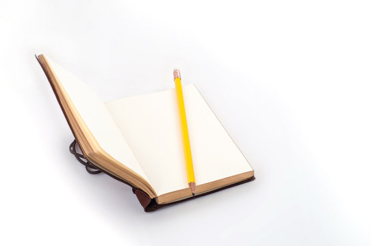 Open empty diary with yellow pencil on table