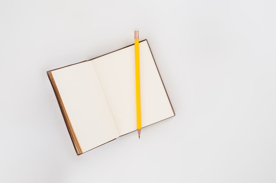 Open empty diary with yellow pencil on table