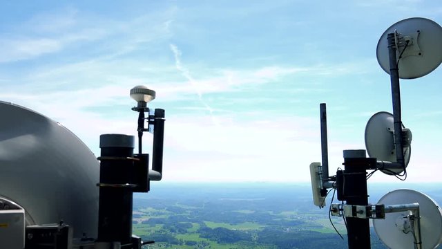 White parabolic antennas in a rural area, a countryside and the bright blue sky in the background