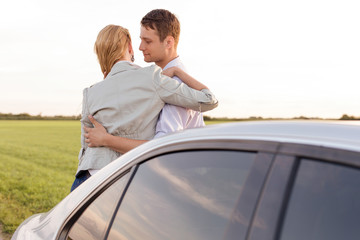Fototapeta na wymiar Romantic young couple leaning on car during road trip
