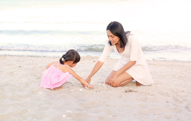 Fototapeta na wymiar Happy loving family. Mother and her daughter child girl playing sand at the beach