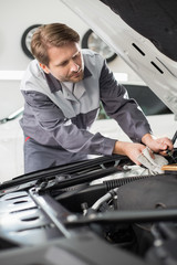 Male mechanic repairing car engine in workshop