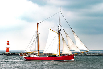 Fototapeta na wymiar Sailing ship on the sea. Red Tall Ship and Lighthouse