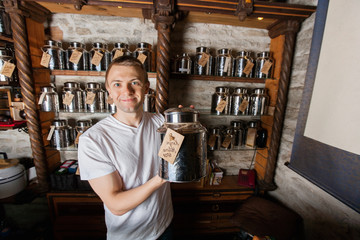 Portrait of smiling male owner displaying tea container in store