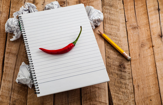 Chili pepper on blank lined paper of notebook with crumpled paper balls as concept of Hot and Creative idea on paper