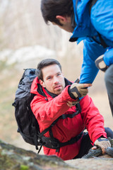 Fototapeta premium Male hiker helping friend while trekking in forest