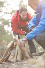 Fototapeta premium Male hikers lighting bonfire in forest