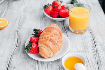 Healthy Breakfast croissant with fresh orange juice and strawberries