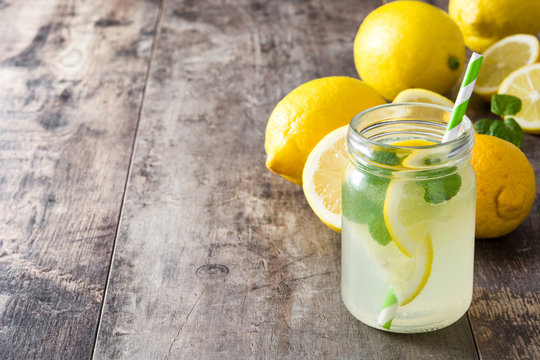 Lemonade drink in a jar glass on wooden background. Copyspace.
