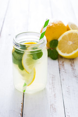 Lemonade drink in a jar glass on white wooden background. Copyspace.
