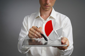 Man in white shirt working with pie chart on a tablet computer, application for budget planning or...