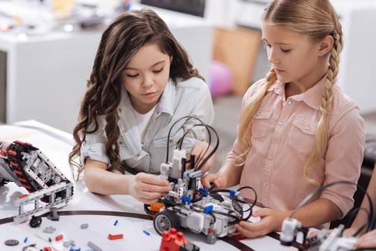 Smart schoolgirls testing electronic robots at school