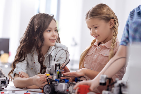 Happy schoolgirls testing electronic robots at school