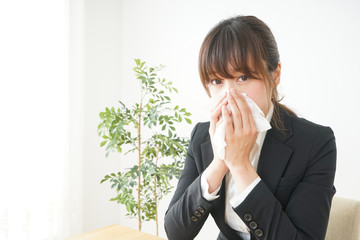 ティッシュで鼻をかむ若い女性