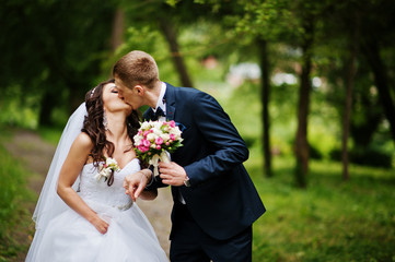 Young stylish wedding couple in love at park.