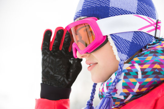 Side view close-up of beautiful young woman in ski goggles looking away