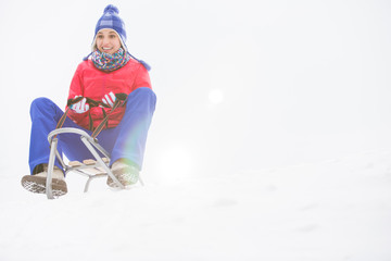 Fototapeta na wymiar Full length of young woman sledging in snow