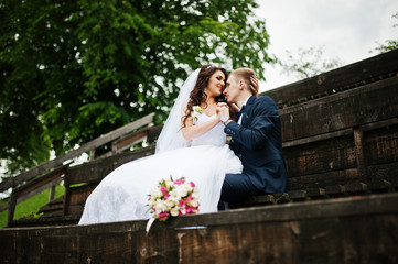 Stylish groom and bride at wooden tribune at their wedding day.
