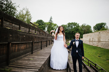 Stylish groom and bride at wooden tribune at their wedding day.