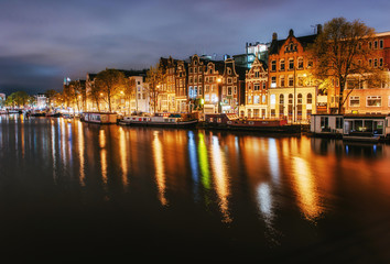 Fototapeta na wymiar Night city view of Amsterdam canal, typical dutch houses and boa