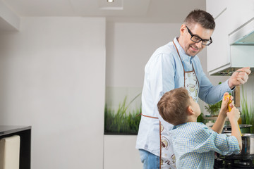 Fototapeta premium Happy father and son preparing spaghetti in kitchen