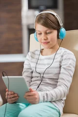 Foto op Plexiglas Cute girl listening music while using digital tablet at home © moodboard