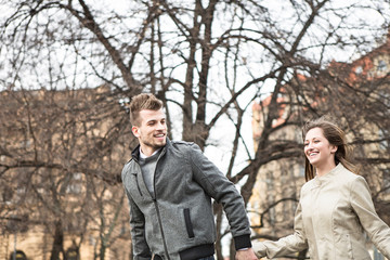 Fototapeta na wymiar Smiling young man and woman holding hands and walking outdoors