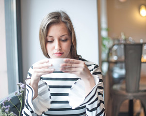 Beautiful young woman drinking coffee in cafe