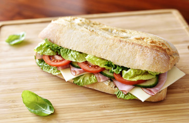 Delicious ciabatta sandwich with ham, tomatoes, fresh salad and cucumber slices.