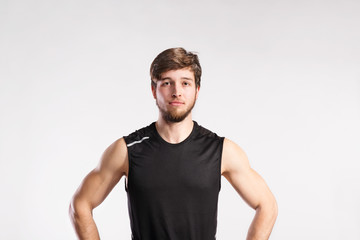 Handsome fitness man in black sleeveless shirt, studio shot.