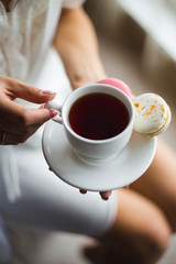 A cup of tea and macaroons in the hands