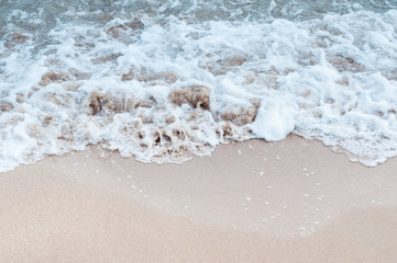 Wave with foam on the sandy beach