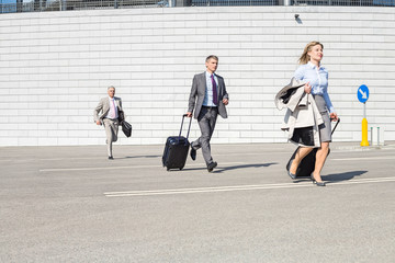 Businesspeople with luggage running on street