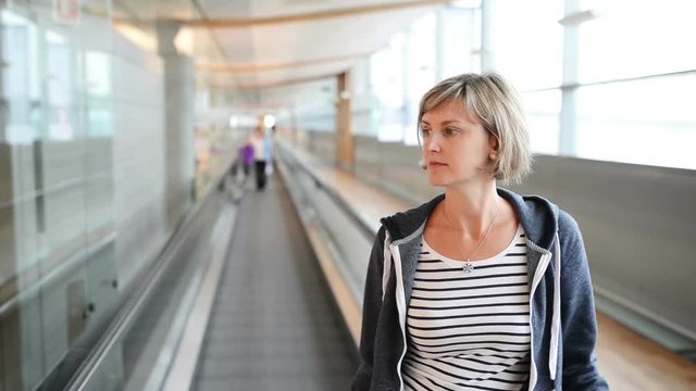 Woman standing on moving walkway inside an airport terminal