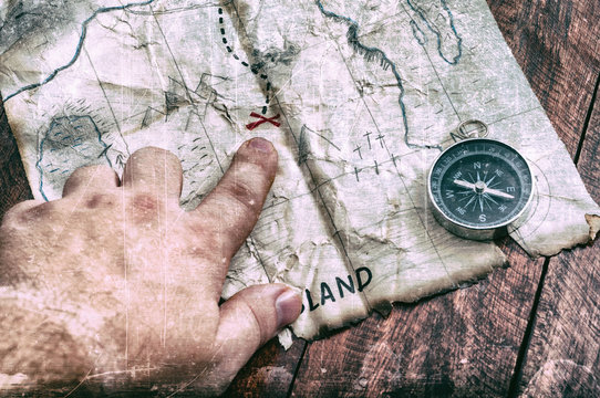 Man point by finger to red cross on vintage old fake pirate map of Treasures. Adventure time