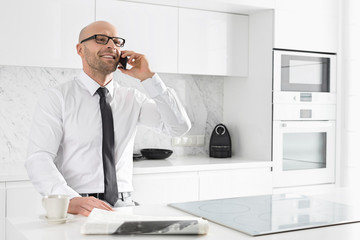 Mid adult businessman on call at kitchen counter