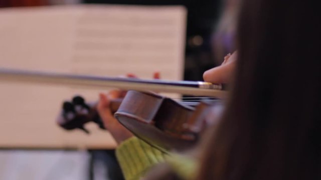 The girl plays the violin well on notes.